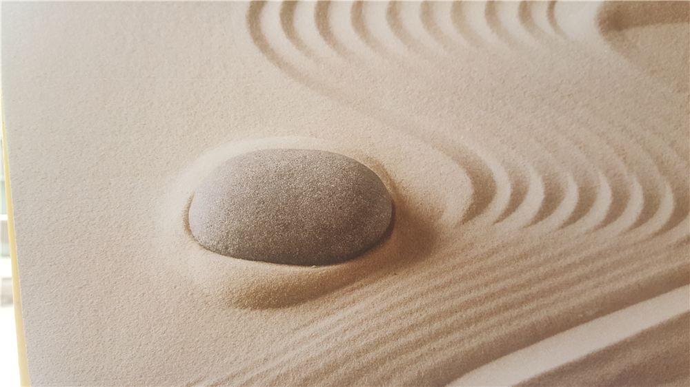 A smooth stone resting on raked sand